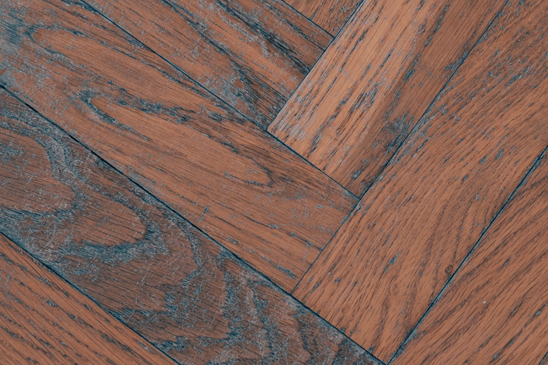 Reddish-brown wooden floor with a herringbone pattern and visible grain.