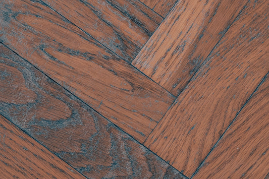 Reddish-brown wooden floor with a herringbone pattern and visible grain.
